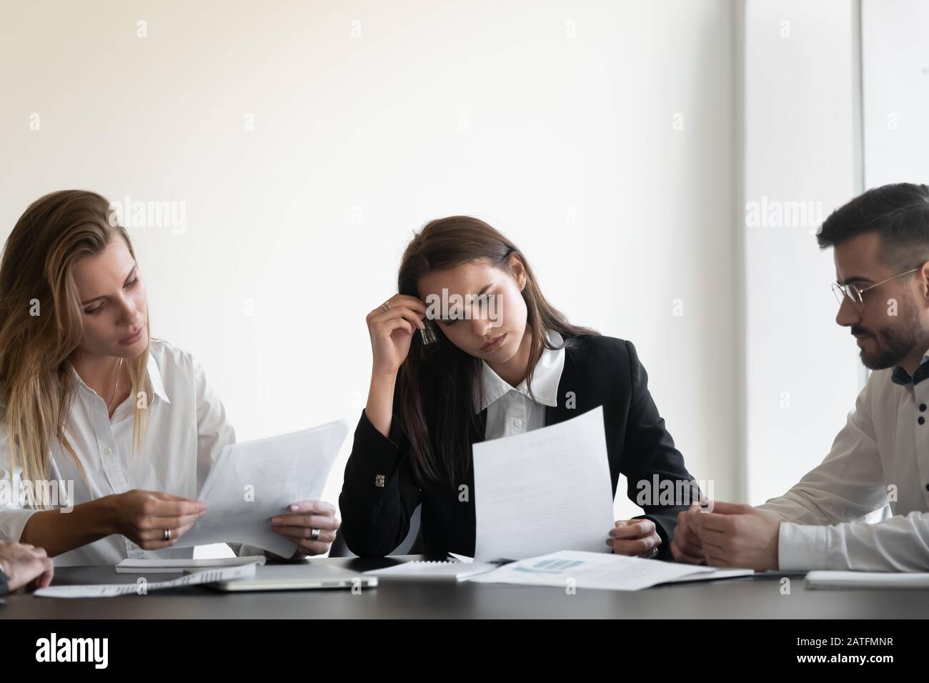 Upset businesspeople sit at desk looking dissatisfied reading financial report Stock Photo