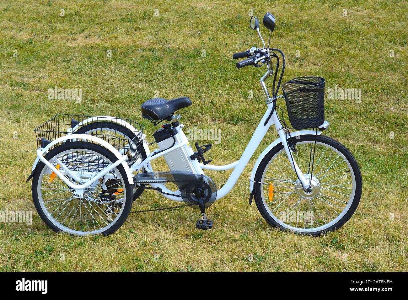 Electric trike or bicycle in the park in sunny summer day. Shot from the side. Unfiltered, with natural lighting. The view of the e motor and power ba Stock Photo