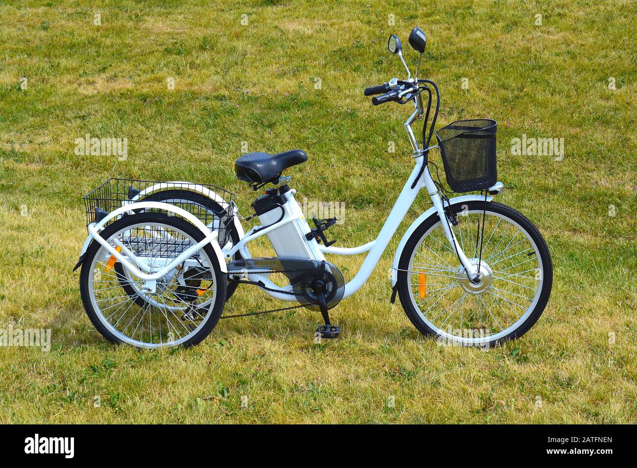 Electric trike or bicycle in the park in sunny summer day. Shot from the side. Unfiltered, with natural lighting. The view of the e motor and power ba Stock Photo