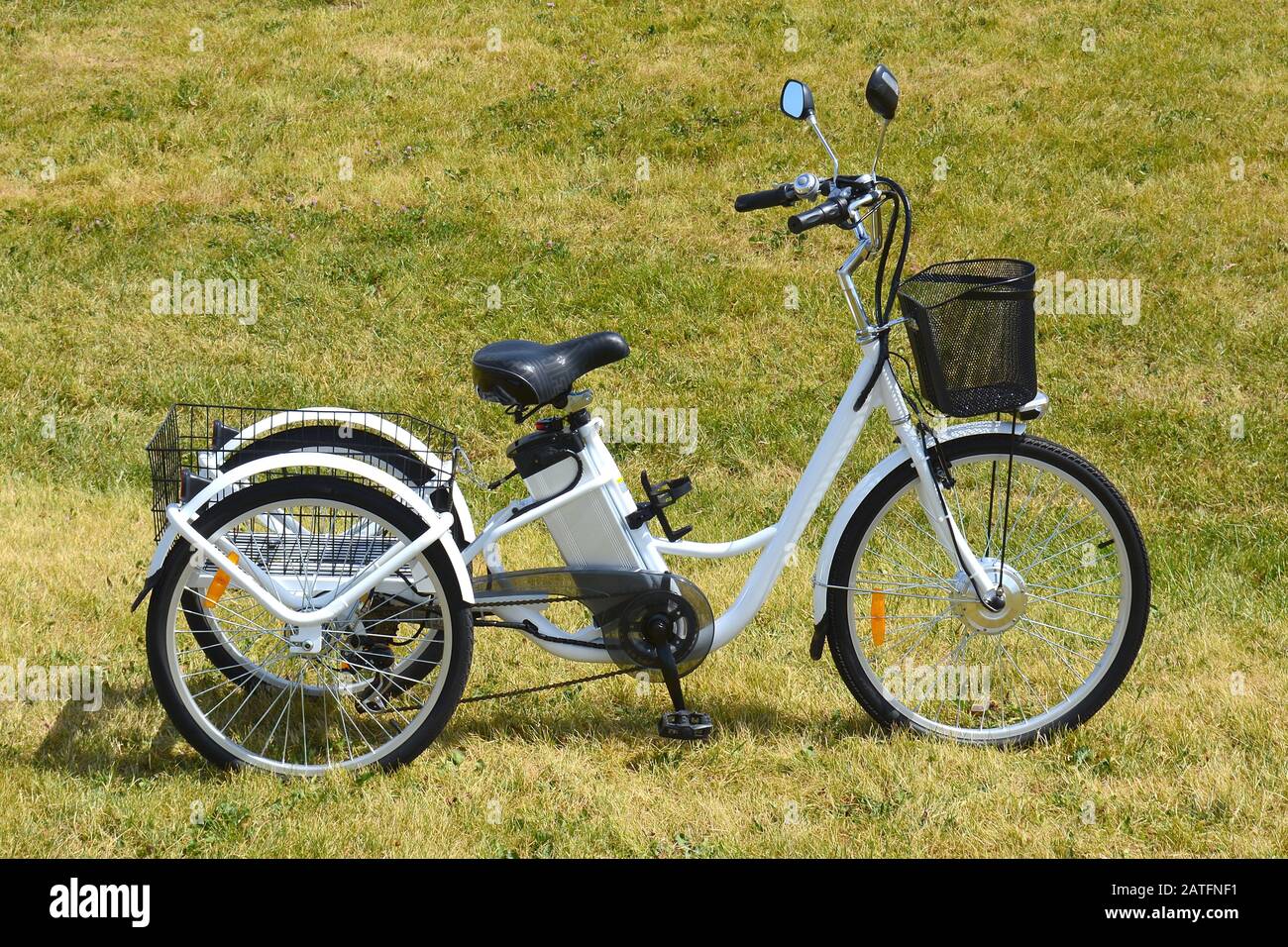 Electric trike or bicycle in the park in sunny summer day. Shot from the side. Natural lighting. View of the e motor and power battery. Stock Photo