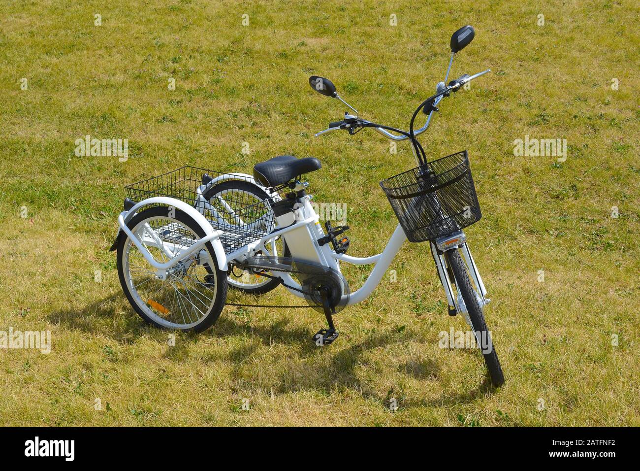 Electric trike or bicycle in the park in sunny summer day. Ebike with lithium battery, shot from the side. Personal transport. Natural lighting. Stock Photo