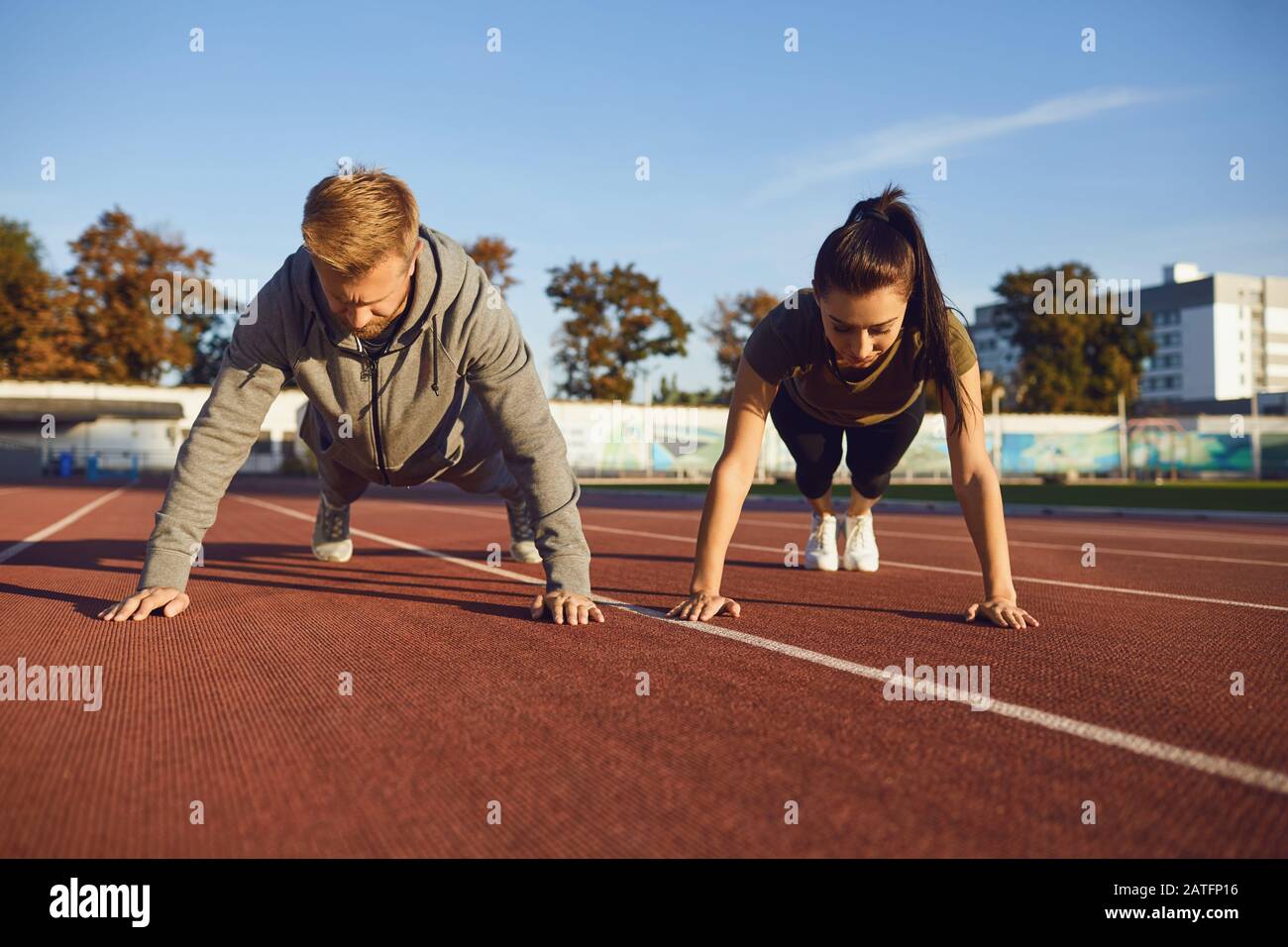 Young couple doing pushups in the stadium Stock Photo