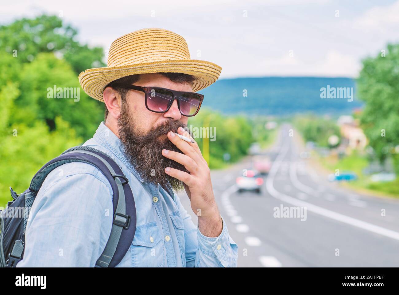 Old habit. Man with beard and mustache in straw hat smoking cigarette, road  background defocused. Traveler stylish hipster take brake with cigarette.  Smoking cigarette before long journey Stock Photo - Alamy