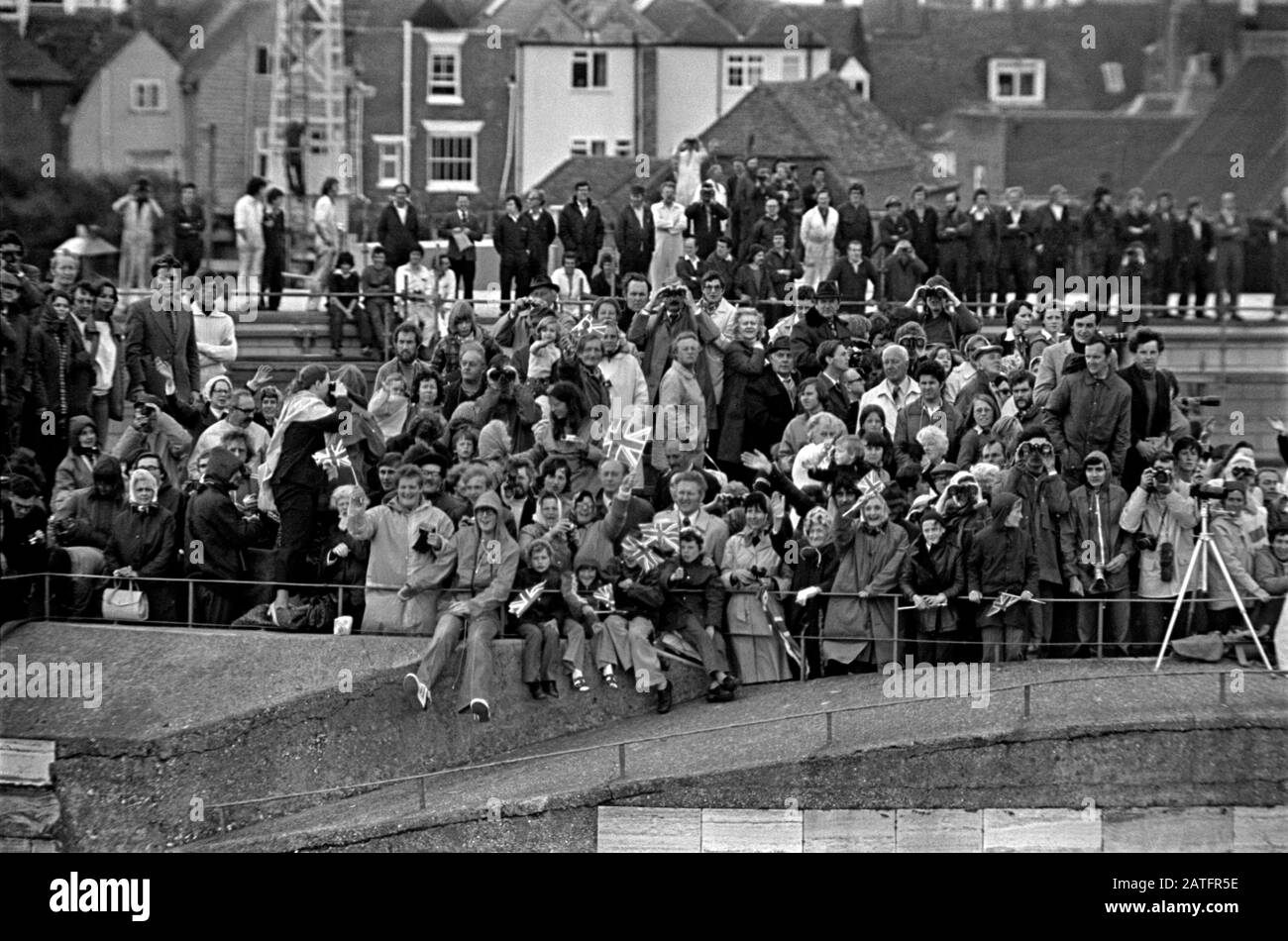 AJAXNETPHOTO. JUNE, 1977. PORTSMOUTH, ENGLAND. - CROWDED TOWER - KING HENRY VIII ROUND TOWER AT THE HARBOUR ENTRANCE FILLED WITH PEOPLE SPECTATING THE DEPARTURE OF SHIPS HEADING FOR SPITHEAD ANCHORAGE AND QUEEN'S SILVER JUBILEE REVIEW. VOSPER THORNYCROFT WORKERS CAN BE SEEN BACKGROUND STANDING ON WORKSHOP ROOF.PHOTO:JONATHAN EASTLAND/AJAX REF:772606 15001 Stock Photo