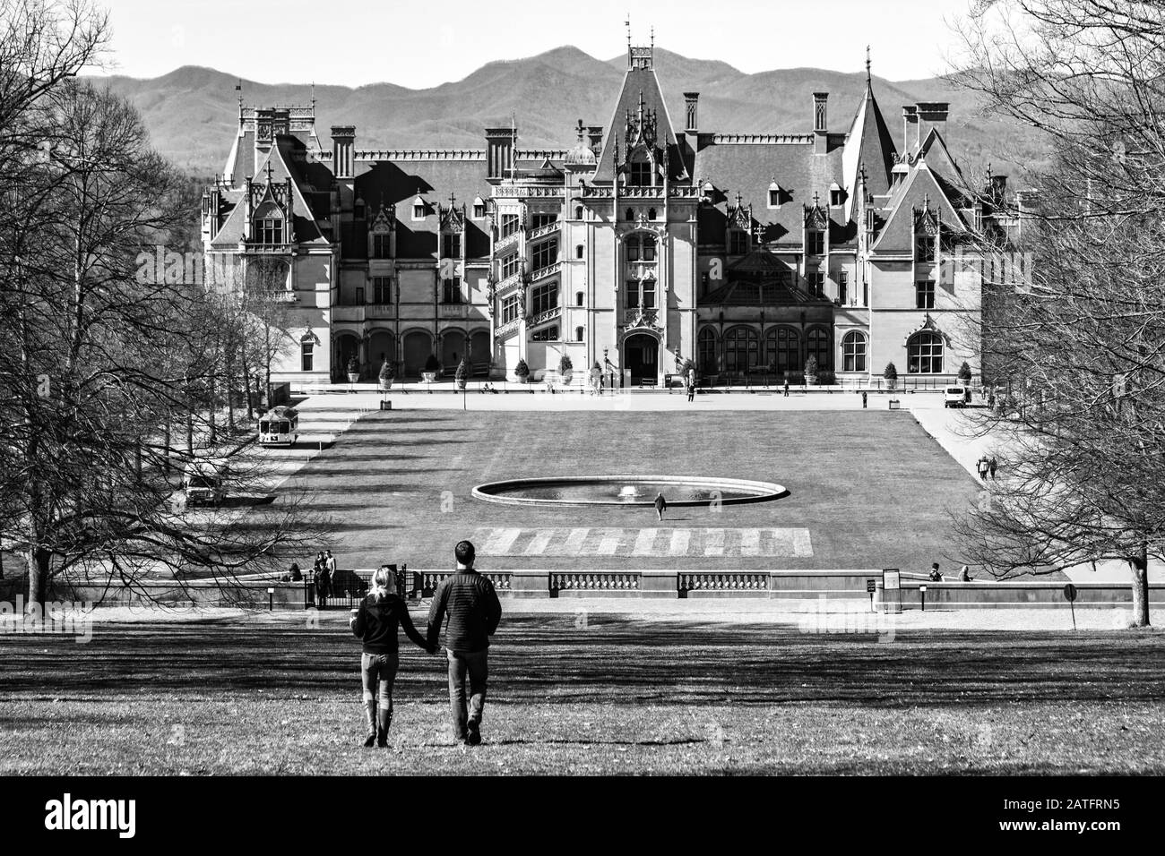 Tourists stroll towards the Biltmore House, with the Blue Ridge Mountains behind it, at the Biltmore Estate in Asheville, NC, USA Stock Photo