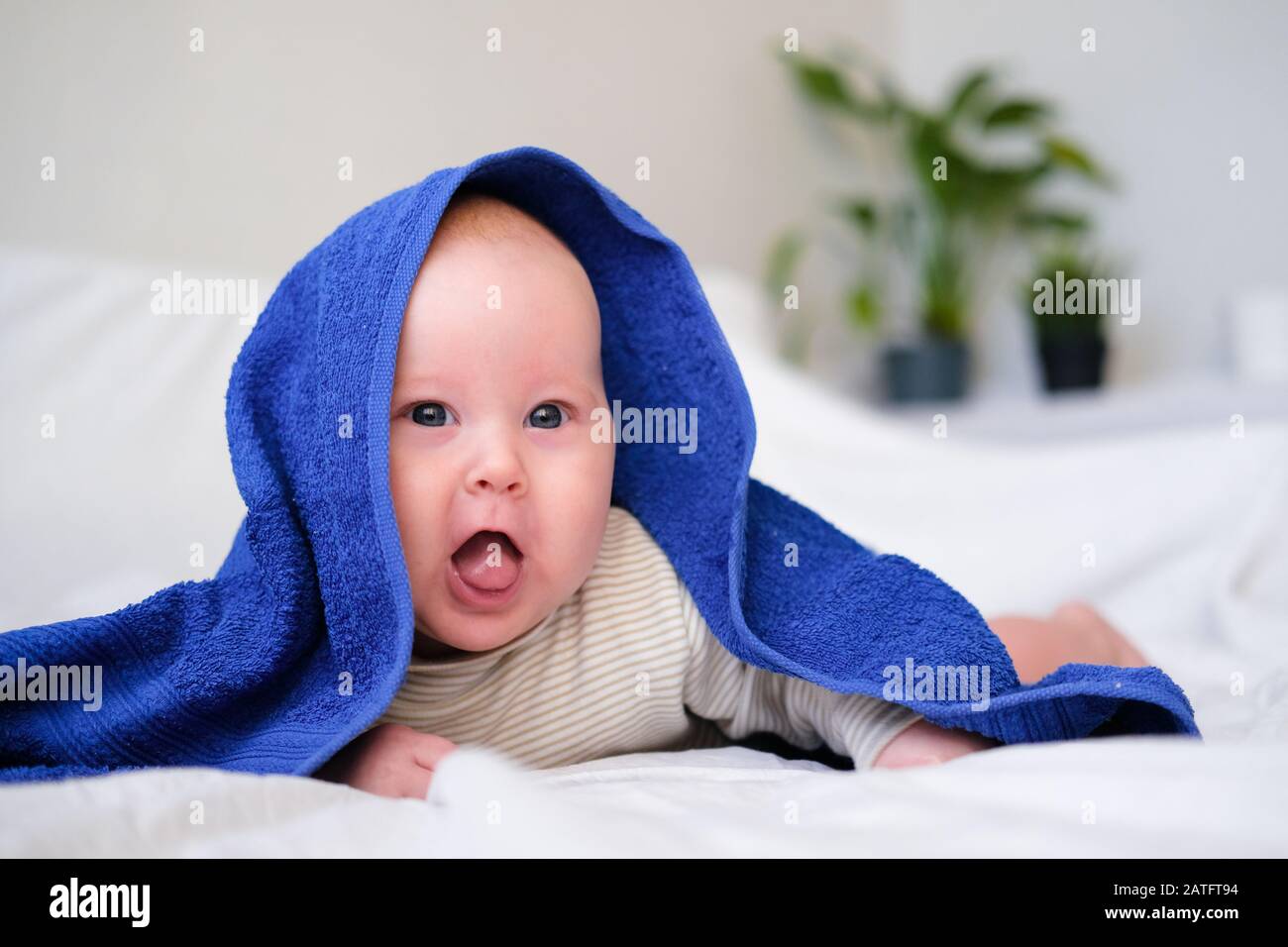 Bath time. Cute smiling caucasian infant baby looking at camera in blue
