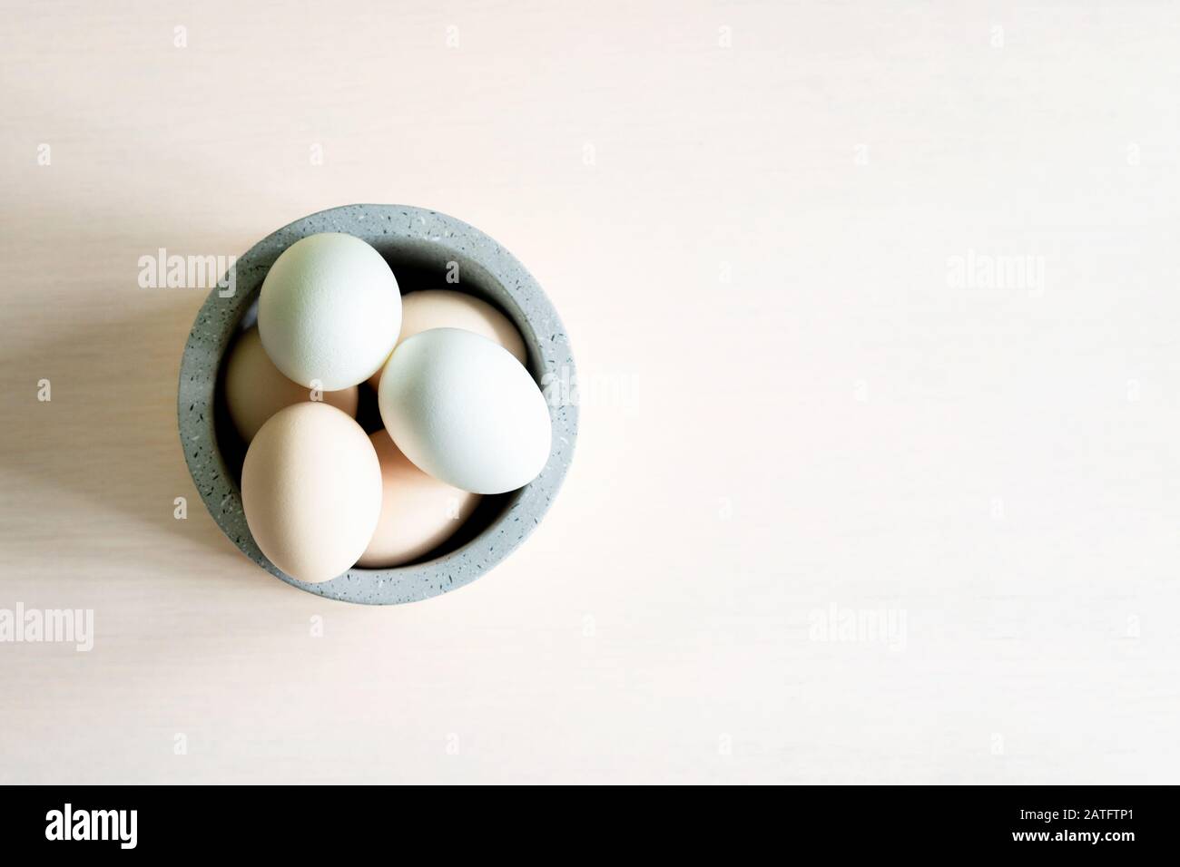 Natural organic Easter eggs and feathers in ceramic bowl on white background. Natural healthy food and organic farming, easter and spring concept. Stock Photo