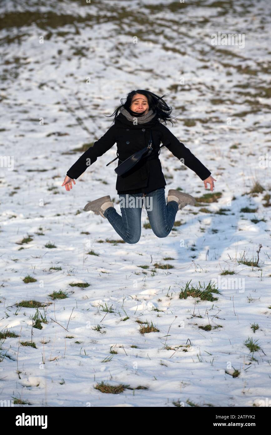 Asian woman jumping in the snow Stock Photo