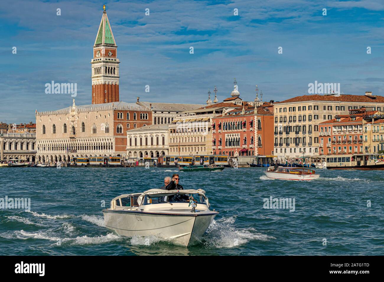 A Water taxi speeds along The waterfront near Piazza San Marco with St Marks Tower and The Doges Palace in the distance ,Venice,Italy Stock Photo