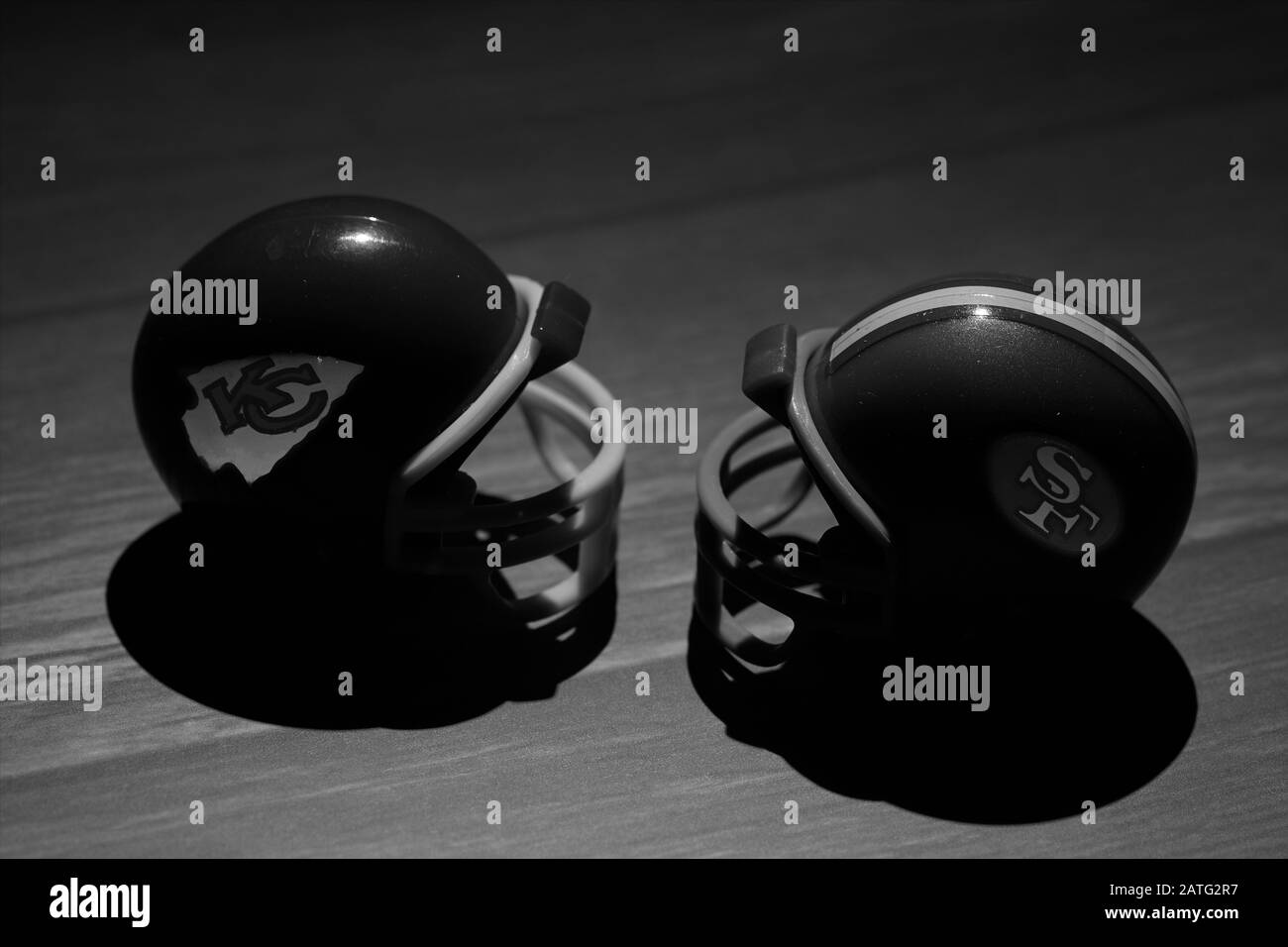Helmets of the NFL Super Bowl LIV teams, the Kansas City Chiefs and the San Francisco 49ers in black and white on wooden background Stock Photo