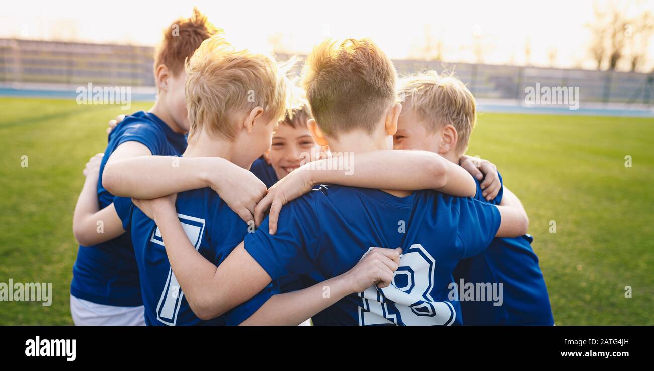 Happy kids in elementary school sports team celebrating soccer succes in tournament final game. Children soccer team team gathering together in a circ Stock Photo