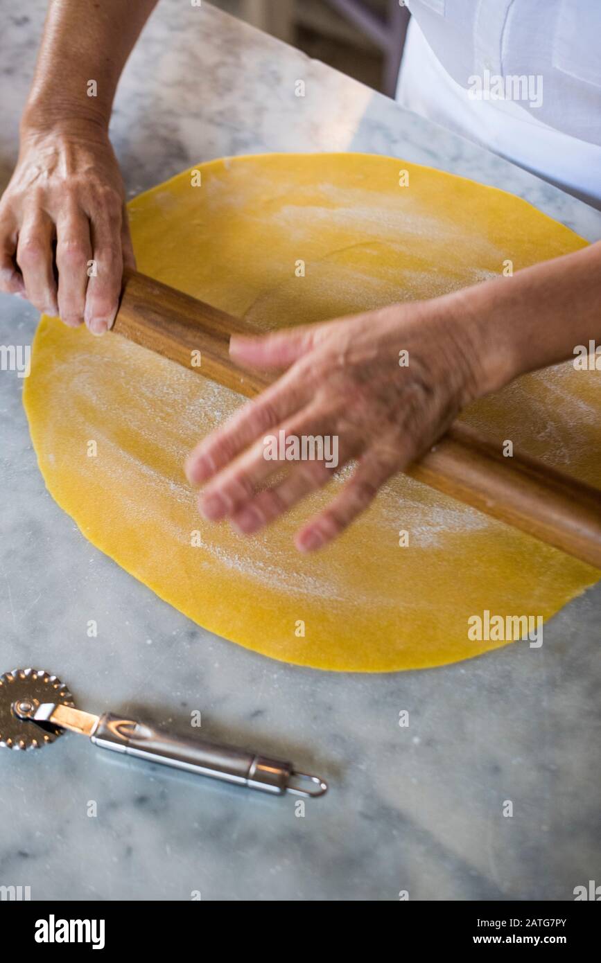 Italian woman hand rolling homemade Tortellini pasta dough Stock Photo