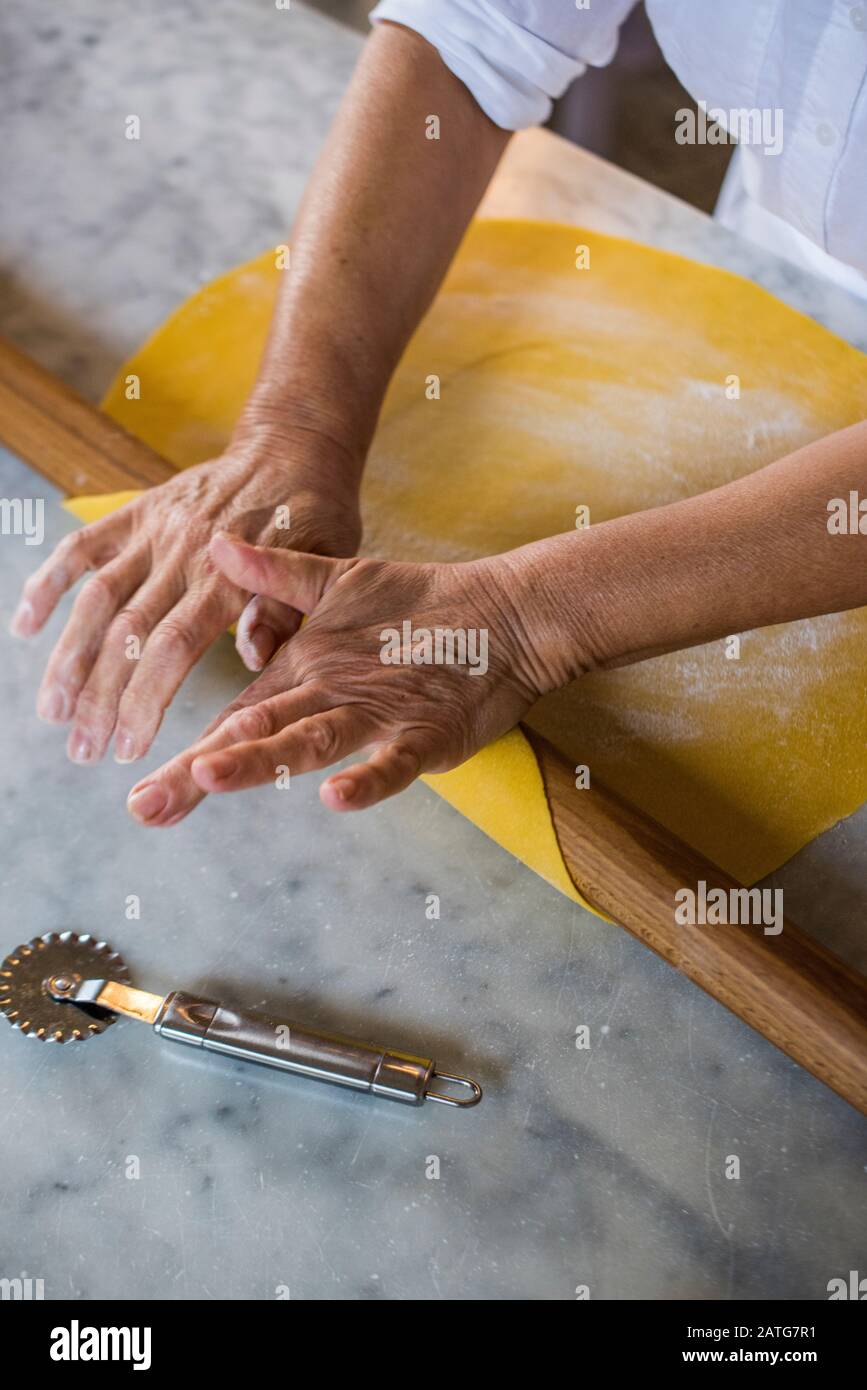 Italian woman hand rolling homemade Tortellini pasta dough Stock Photo