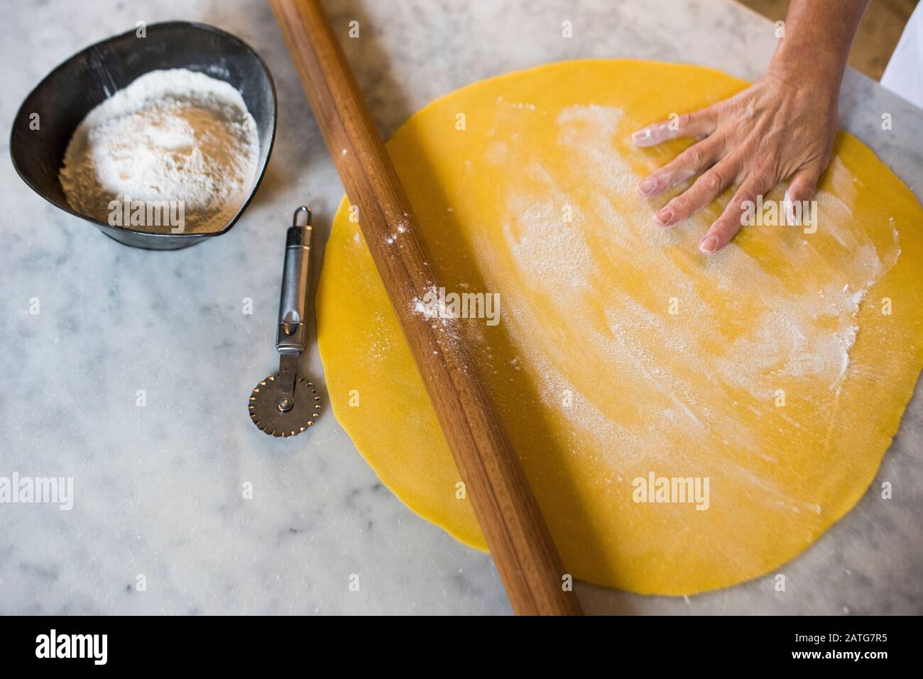 Italian woman hand rolling homemade Tortellini pasta dough Stock Photo