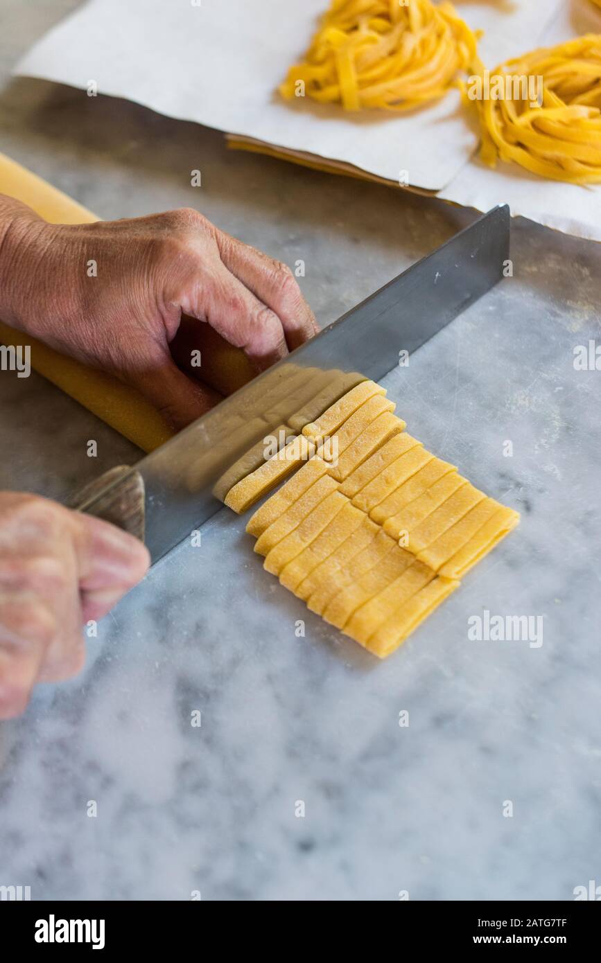 Donna che usa un raschietto per impasti, facendo pasta fresca a casa nella  sua cucina Foto stock - Alamy