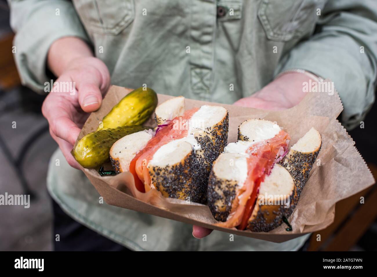 Woman holding poppy seed bagel with lox and cream cheese Stock Photo