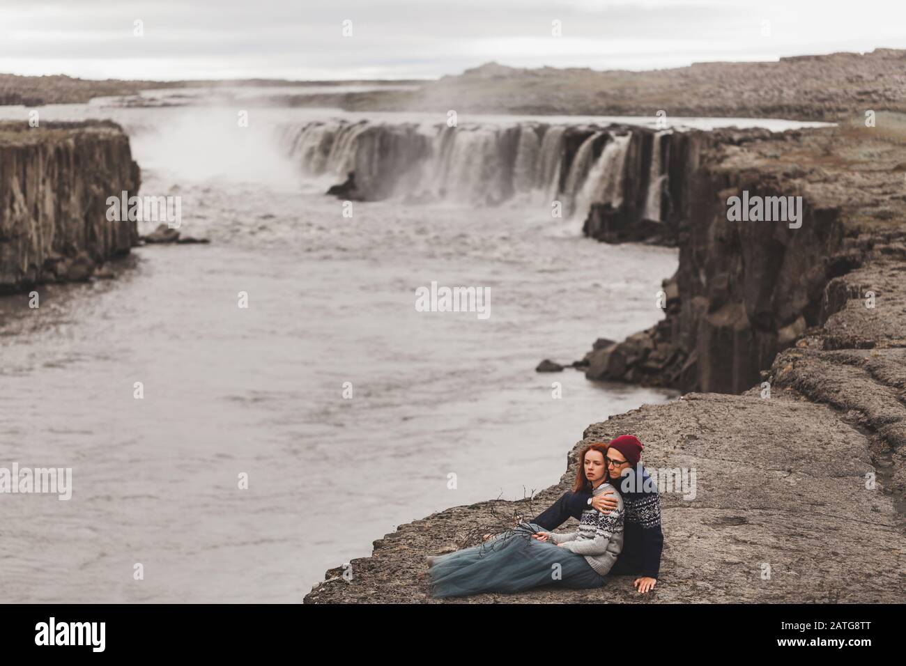 Happy hipster couple in love in Iceland. Traditional wool sweaters, red  hair, gray skirt. Famous Selfoss waterfall on background, dramatic nordic  landscape Stock Photo - Alamy