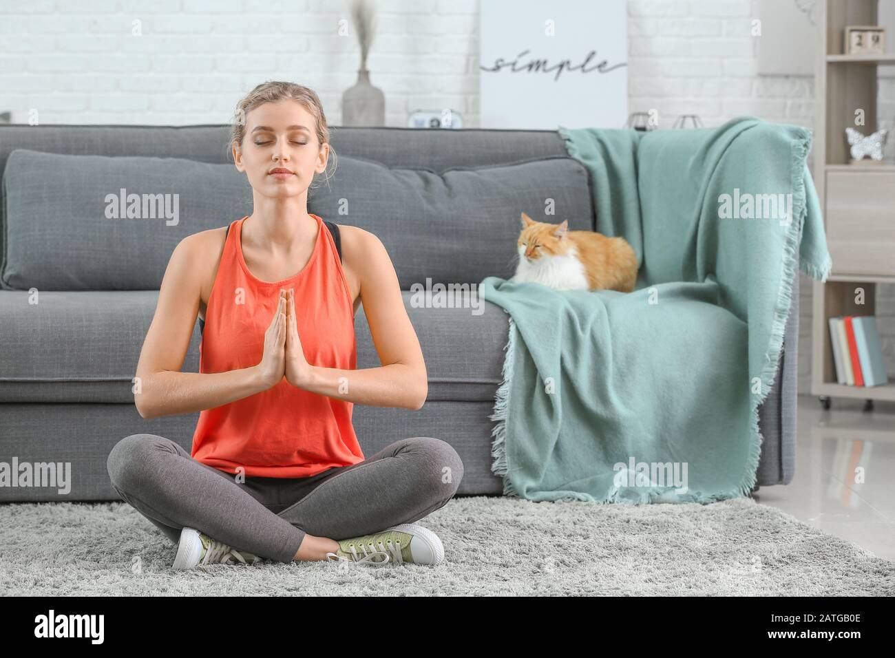 Young woman with cute cat practicing yoga at home Stock Photo - Alamy