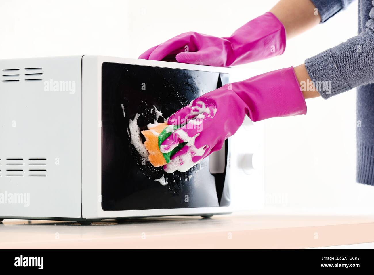 Woman cleaning microwave oven in kitchen Stock Photo