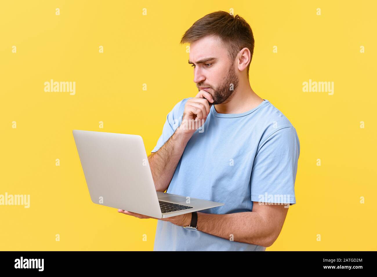 Thoughtful programmer with laptop on color background Stock Photo