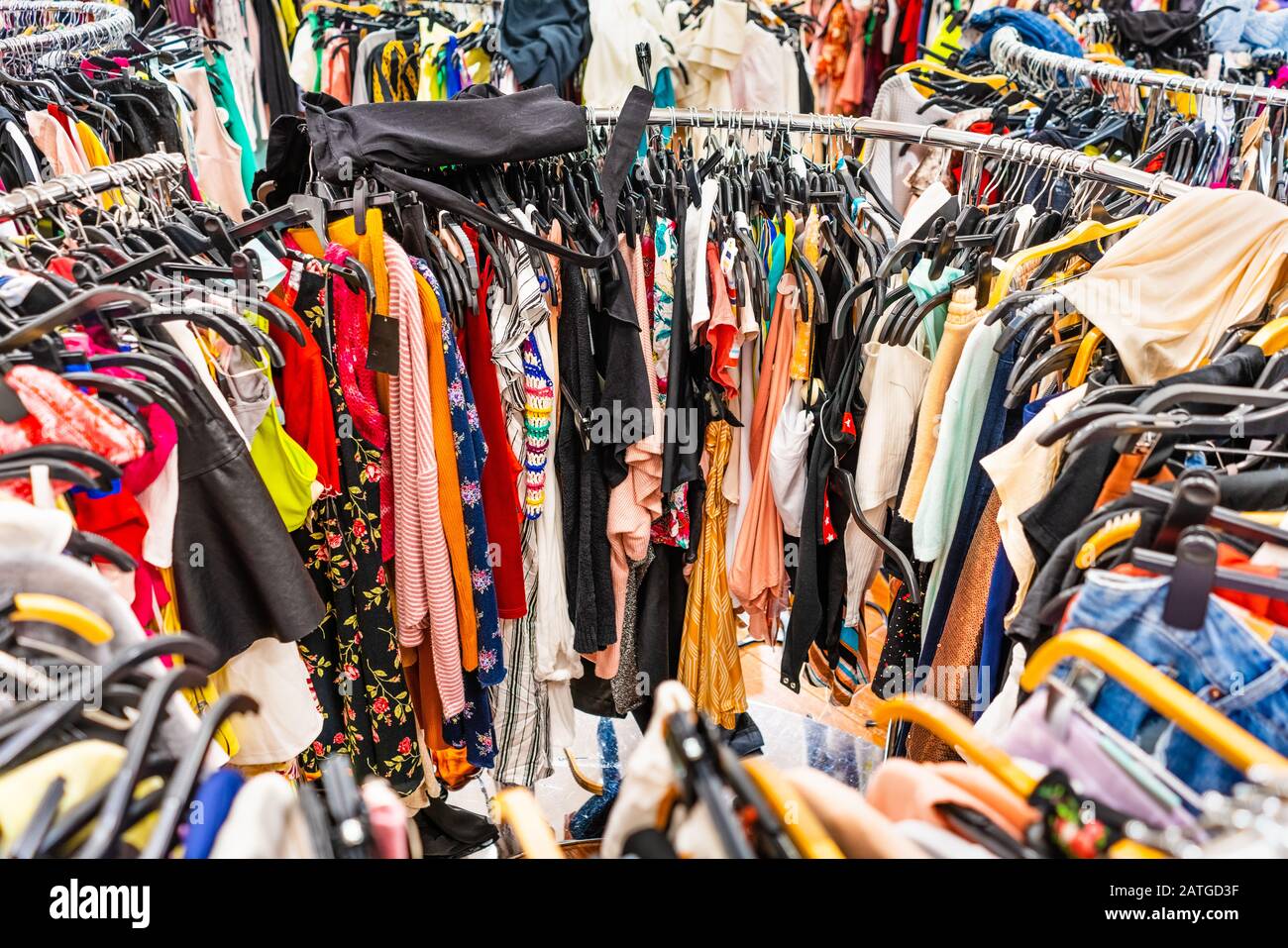 Crowded clearance section in a clothing store, with various colorful garments placed tightly on racks in no particular order; fast fashion concept Stock Photo