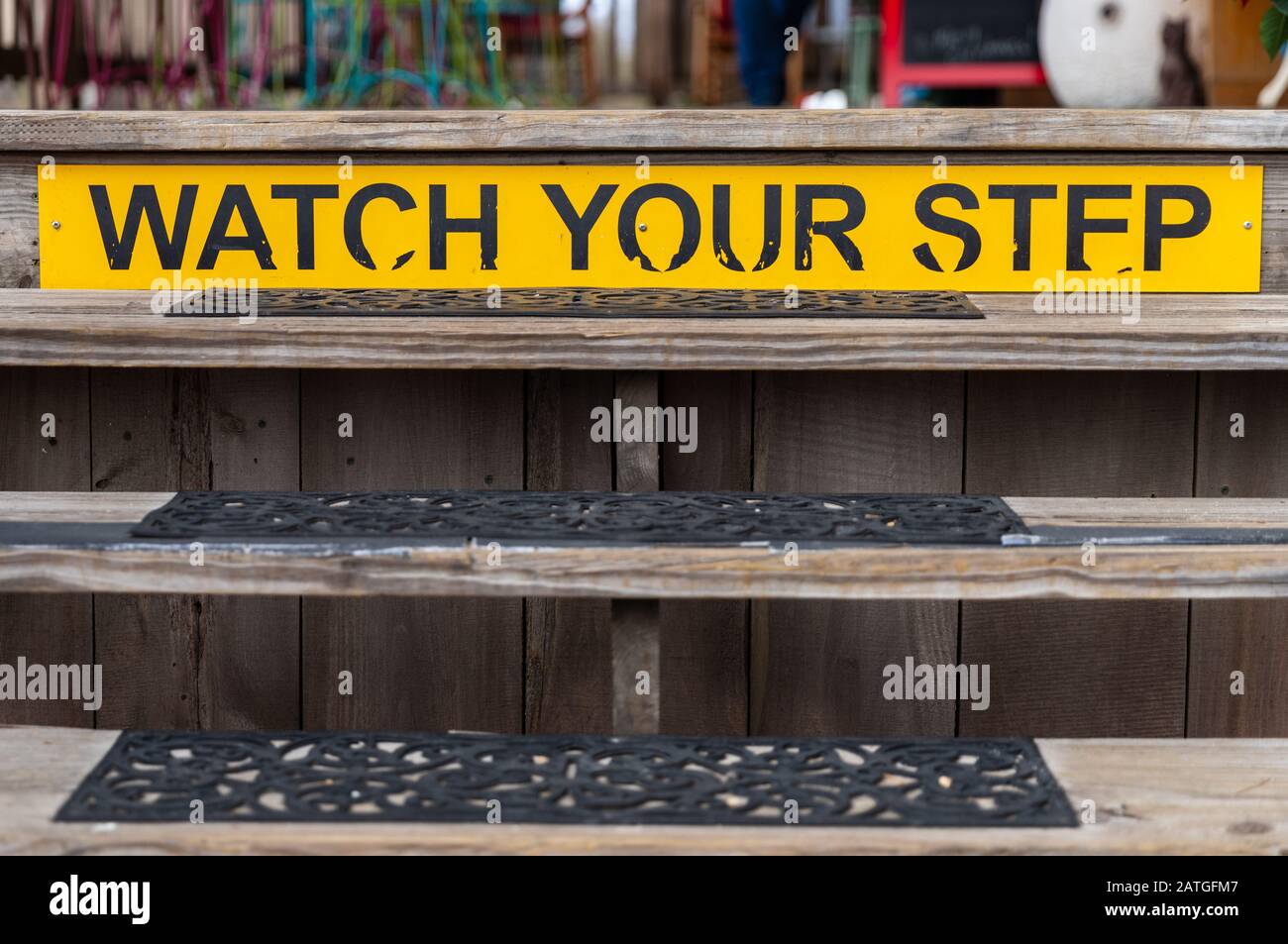 Yellow warning sign, watch your step, on a wooden staircase Stock Photo