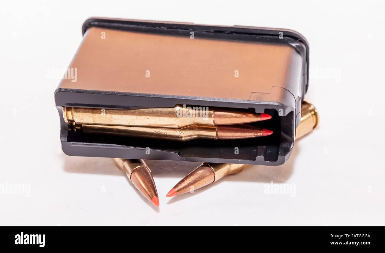 A loaded rifle magazine with two bullets not loaded into it on a white background Stock Photo