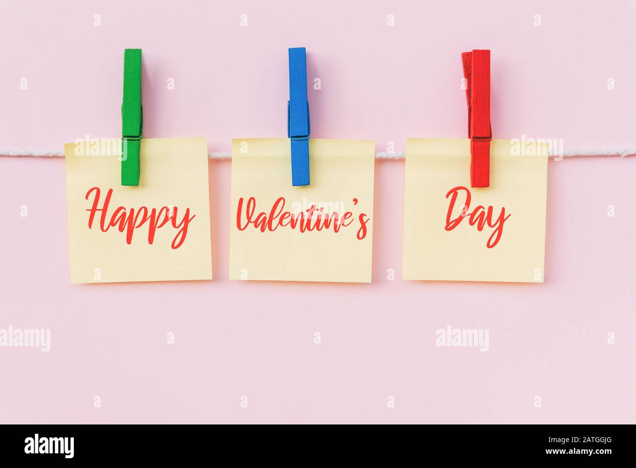Happy Valentine's Day text on hanging paper note. Pink background. Stock Photo