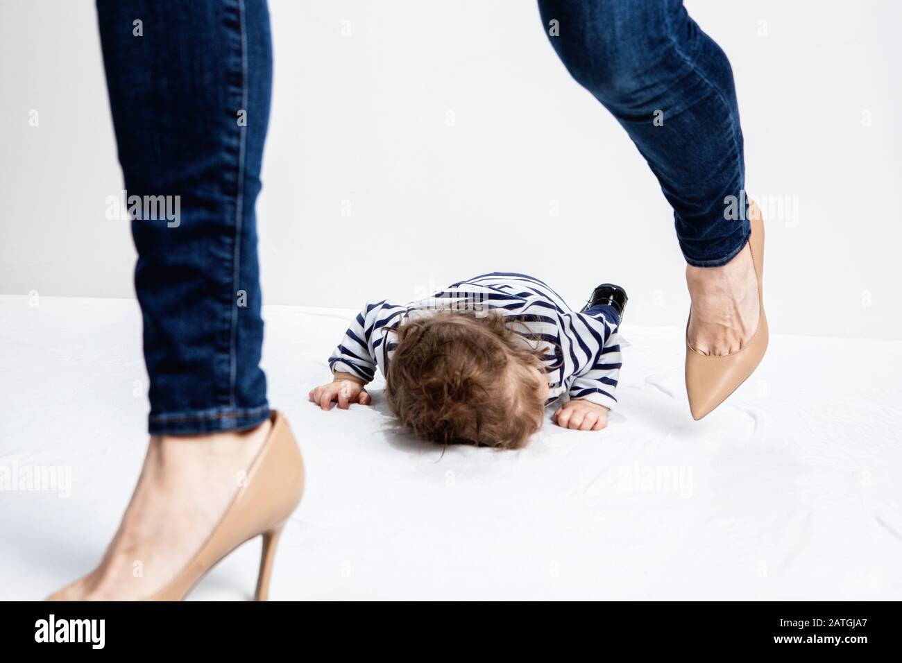 toddler throwing a tantrum laying on the floor with mother walking away angry and frustrated Stock Photo