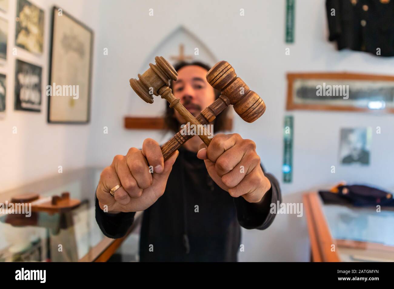 A man holding two wooden hammers or judge gavels crossed. Concept or