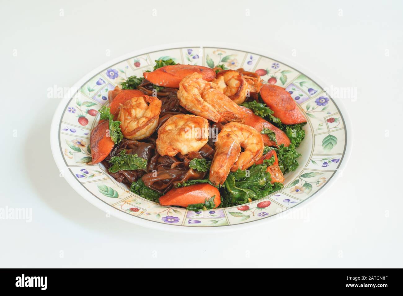 Stir fried Flat Noodle with black soy sauce, shrimps, Kale and Sausages. Thai food from chinese culture. Stock Photo