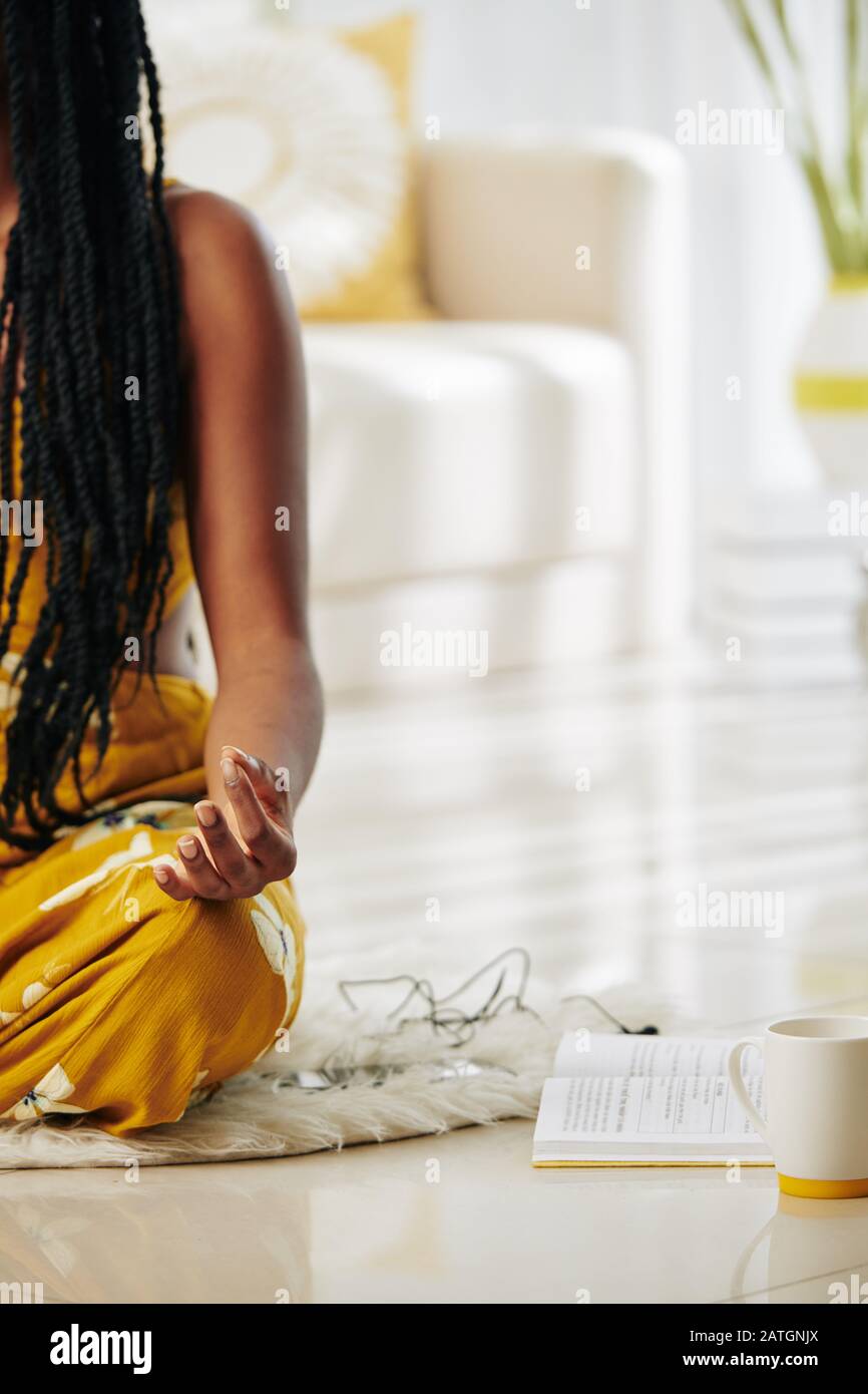 Cropped image of woman practicing meditation at home after reading book with affirmations Stock Photo