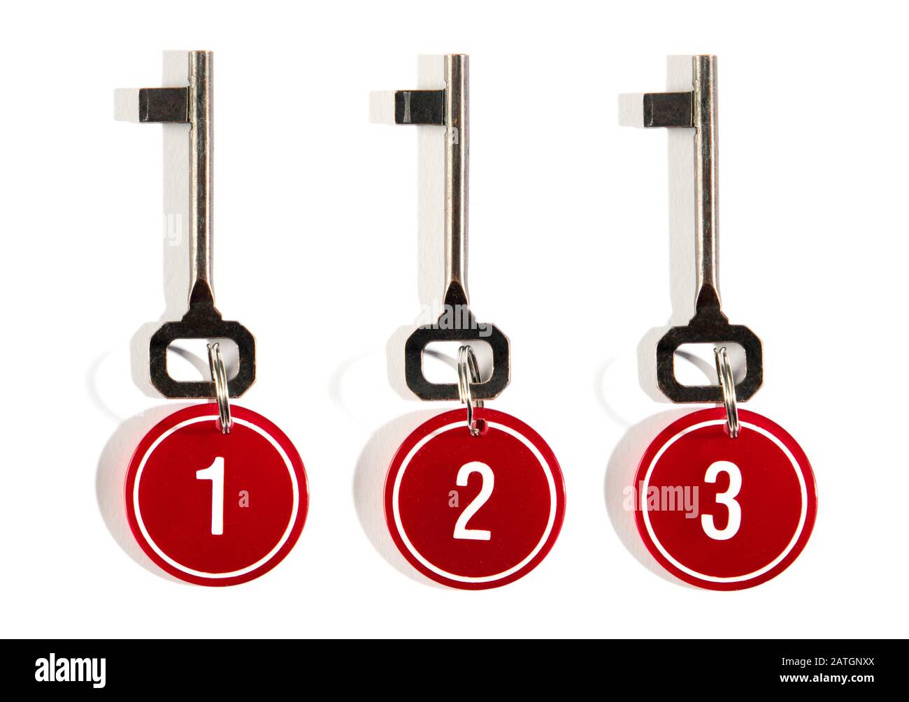 Three matching keys with red numbers on circular key tags on rings arranged in a row on white with shadow Stock Photo