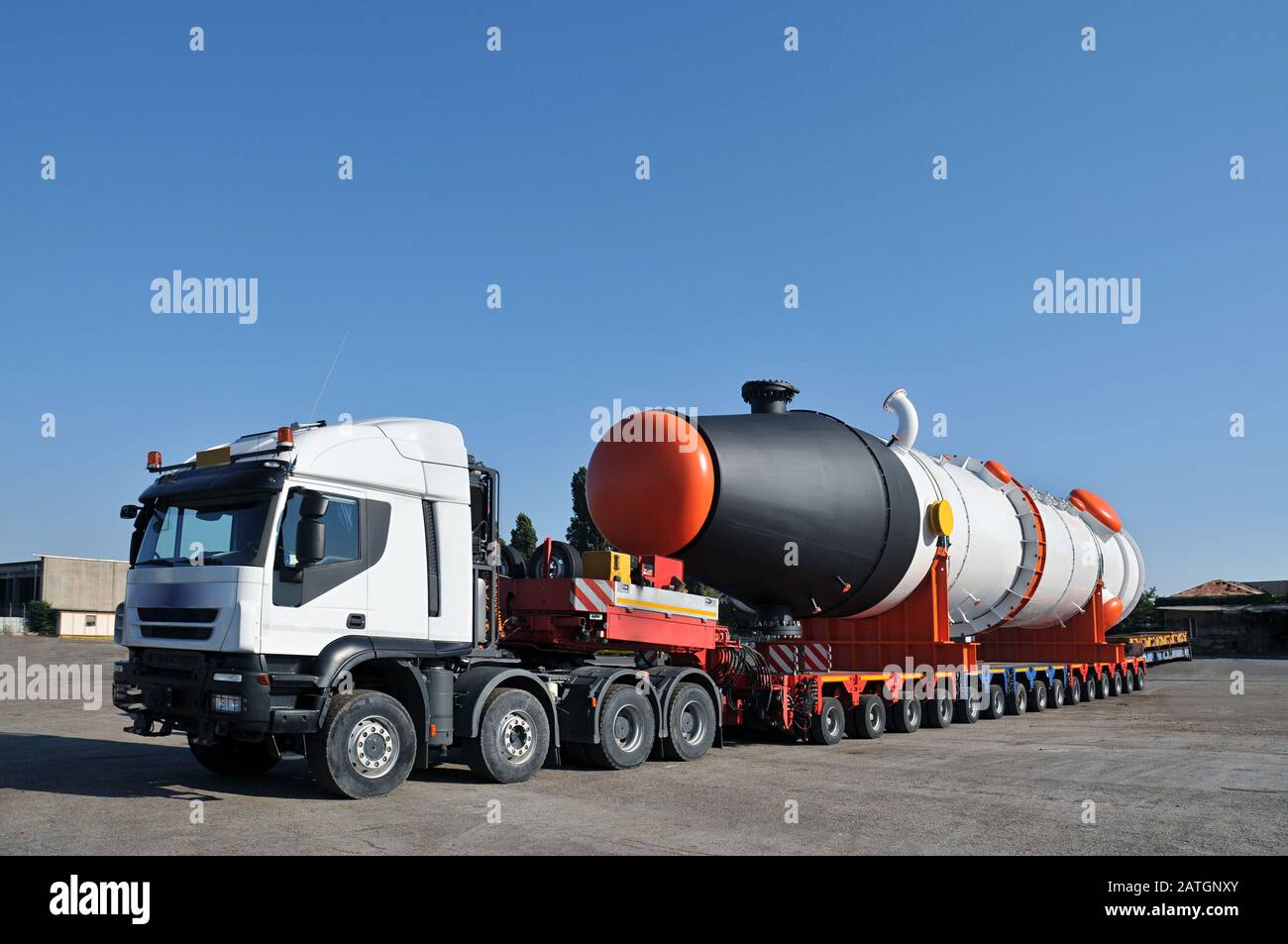 Oversize transport truck with multiple wheels and long storage tank on the tailer parked in a forecourt Stock Photo