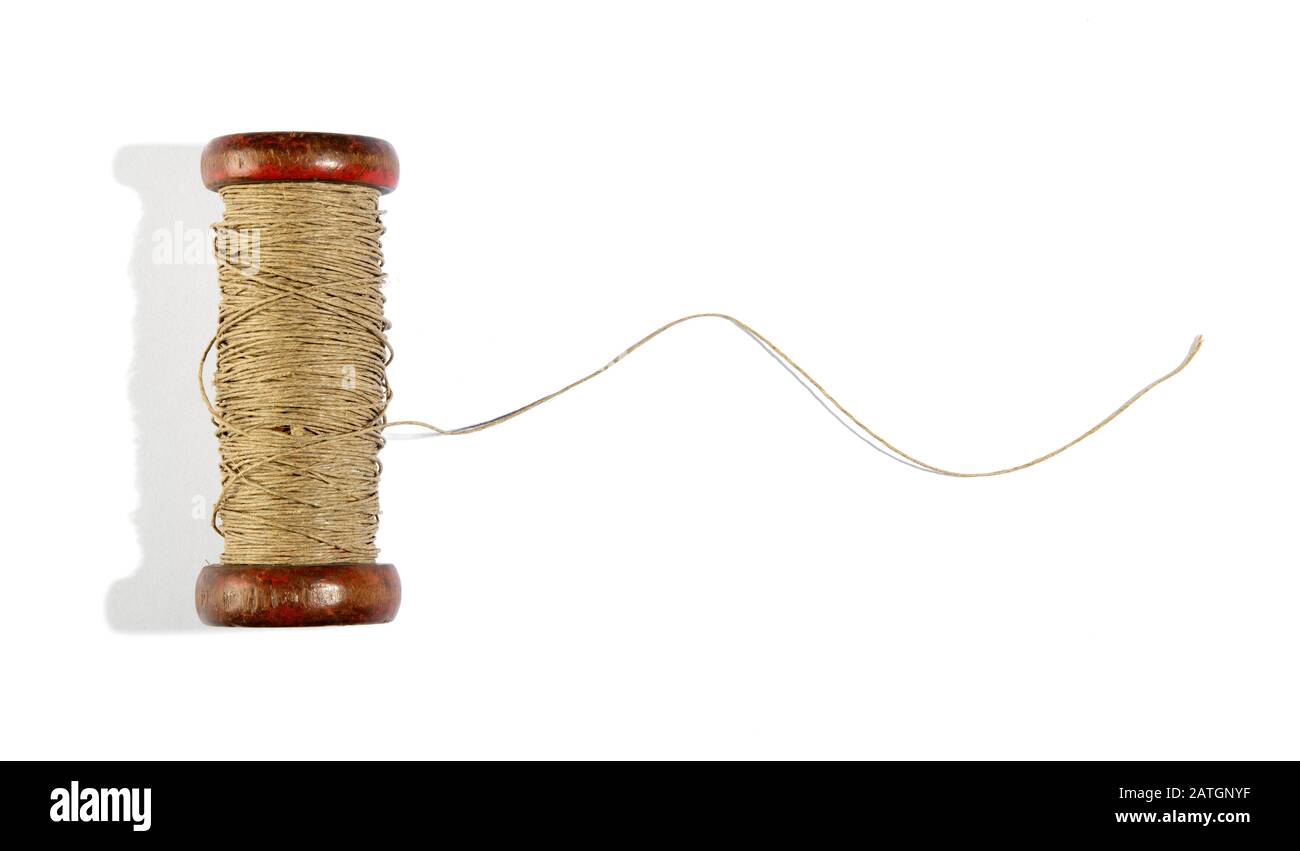 Wooden vintage reel of twine on white with a length of the thread unravelled and copy space Stock Photo
