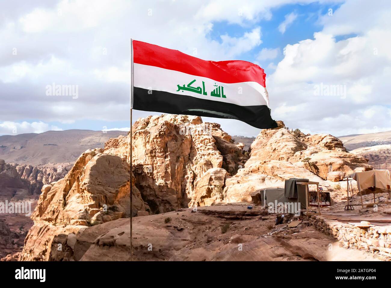 Flag of Islamic republic of Iraq waving in mountain background and cloudy skies Stock Photo