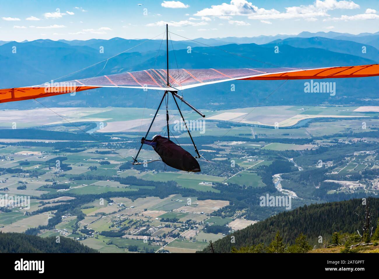 Hang glider in soaring flight off. Recreational extreme air sport for brave hobbyists. Flight over Kootenay valley mountains, Canada Stock Photo