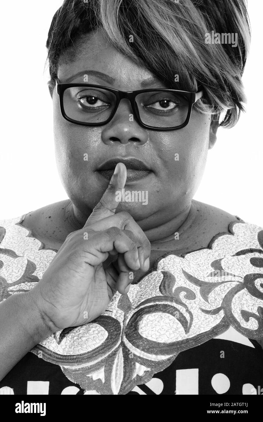 Face of fat black African woman with finger on lips Stock Photo