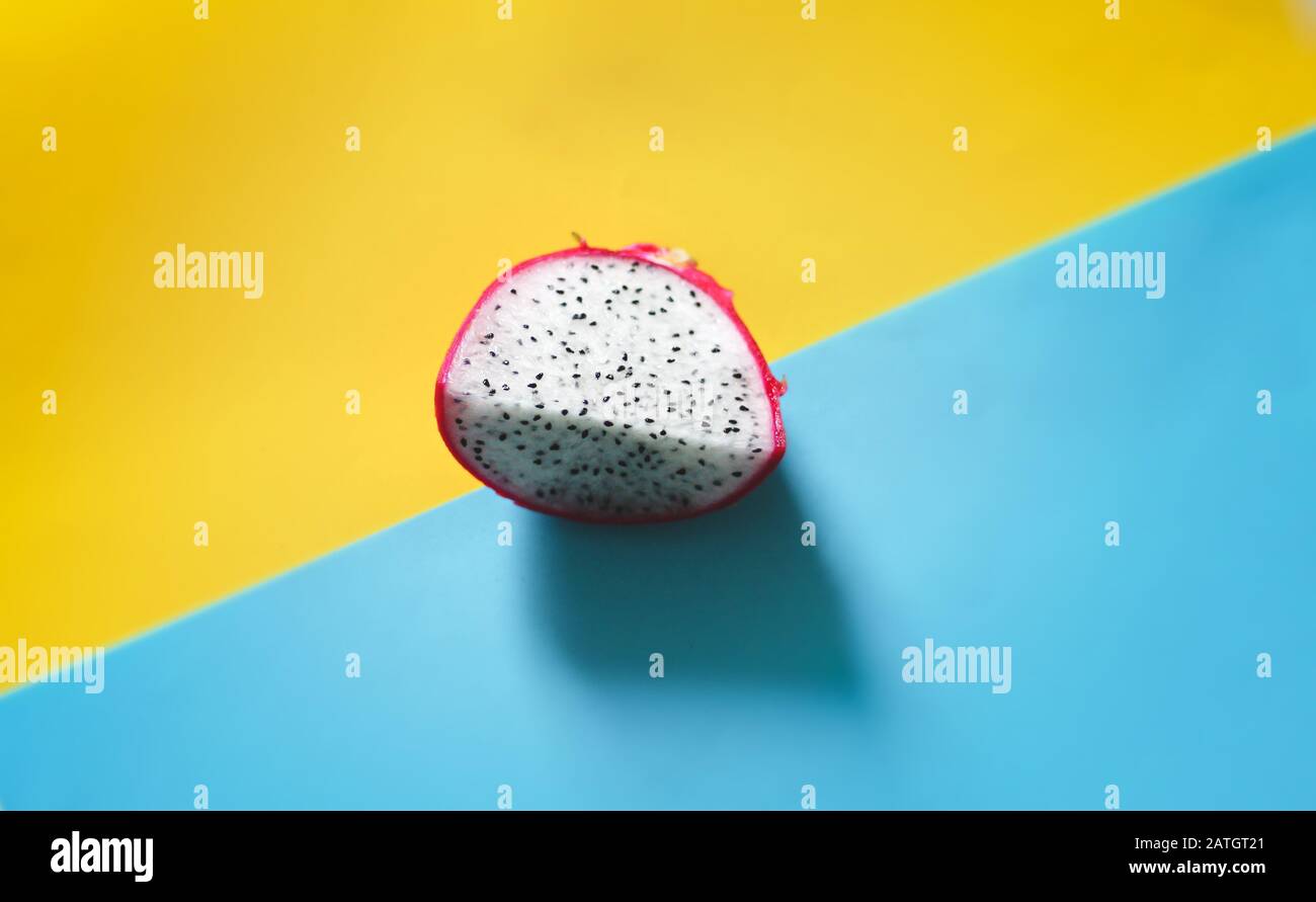 Fresh sliced dragonfruit or pitaya against a bright blue and yellow background to show color contrast, concept of fun, summer and pop culture Stock Photo