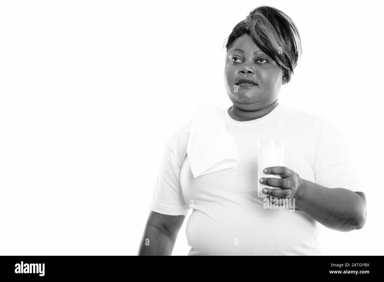 Studio shot of fat black African woman thinking while holding glass of ...