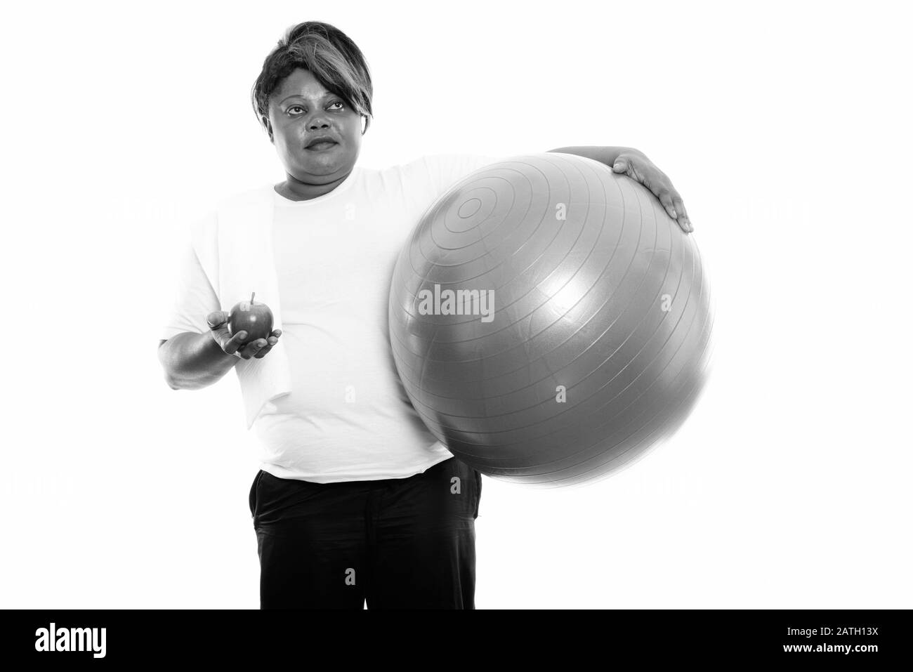 Studio shot of fat black African woman thinking while holding exercise ...
