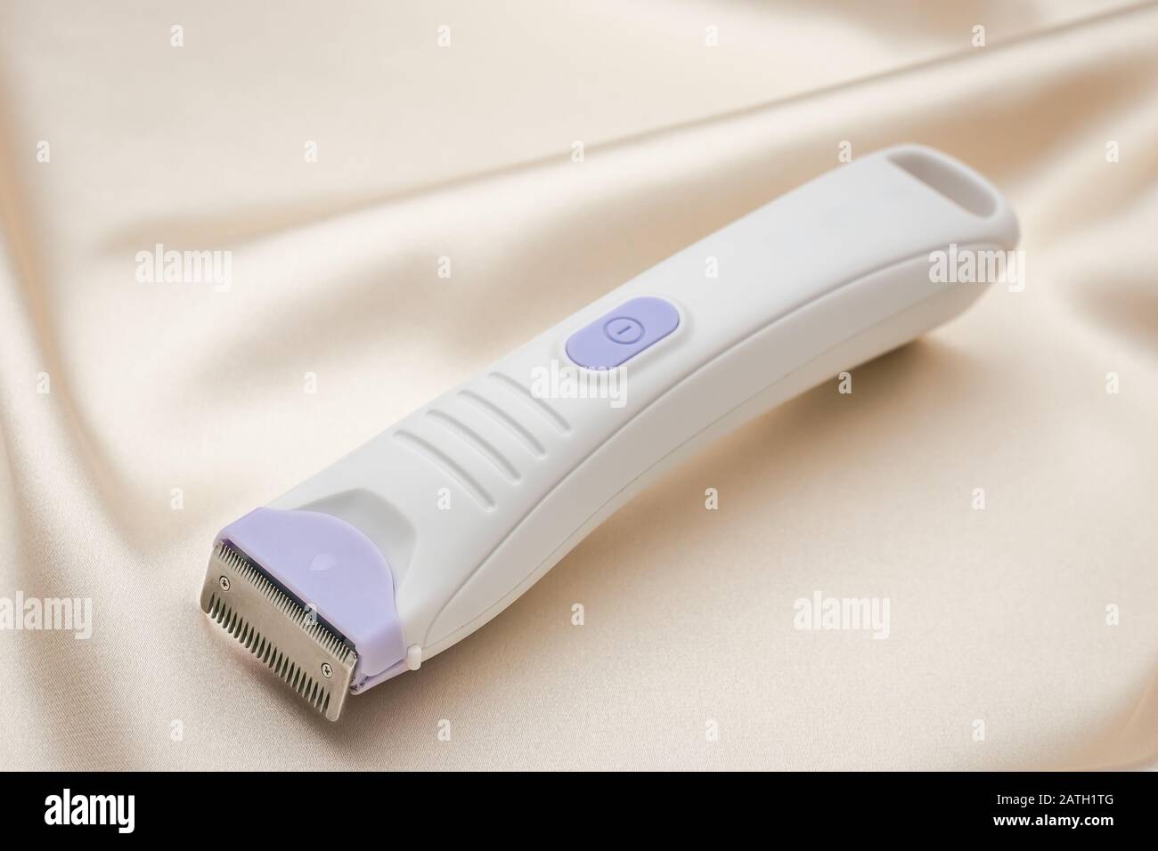 Electric hair trimmer. Personal hygiene item for women. Hair cutting  accessory with metal blade on light fabric background Stock Photo - Alamy