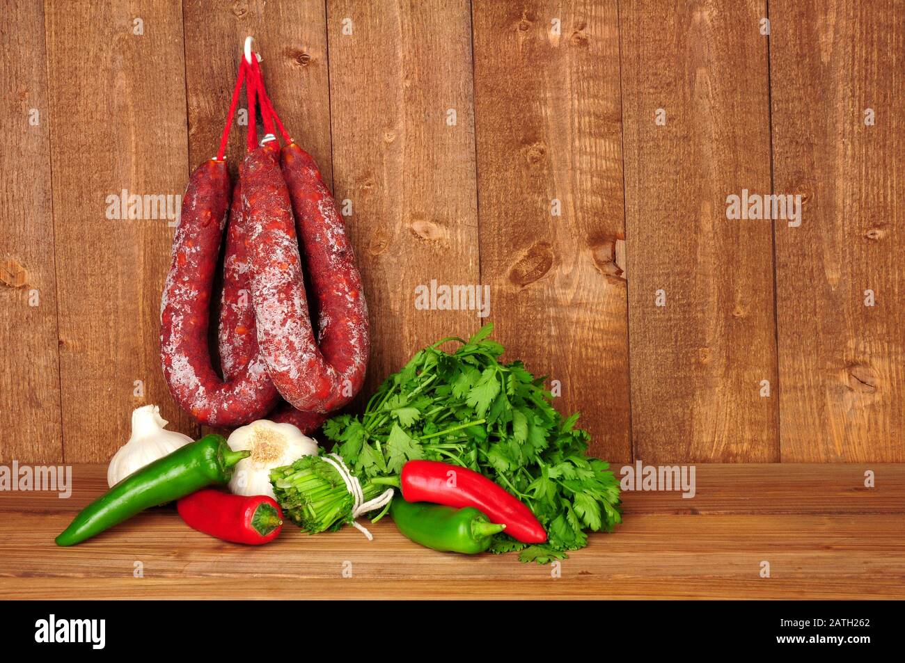 Spicy chorizo salami sausages hanging on a rustic wooden background