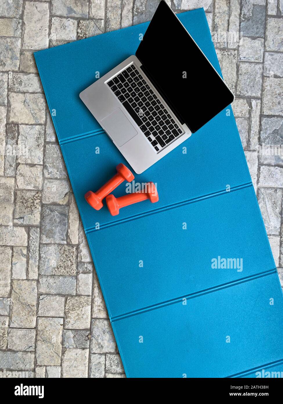 Exercise mat with a laptop and weights Stock Photo