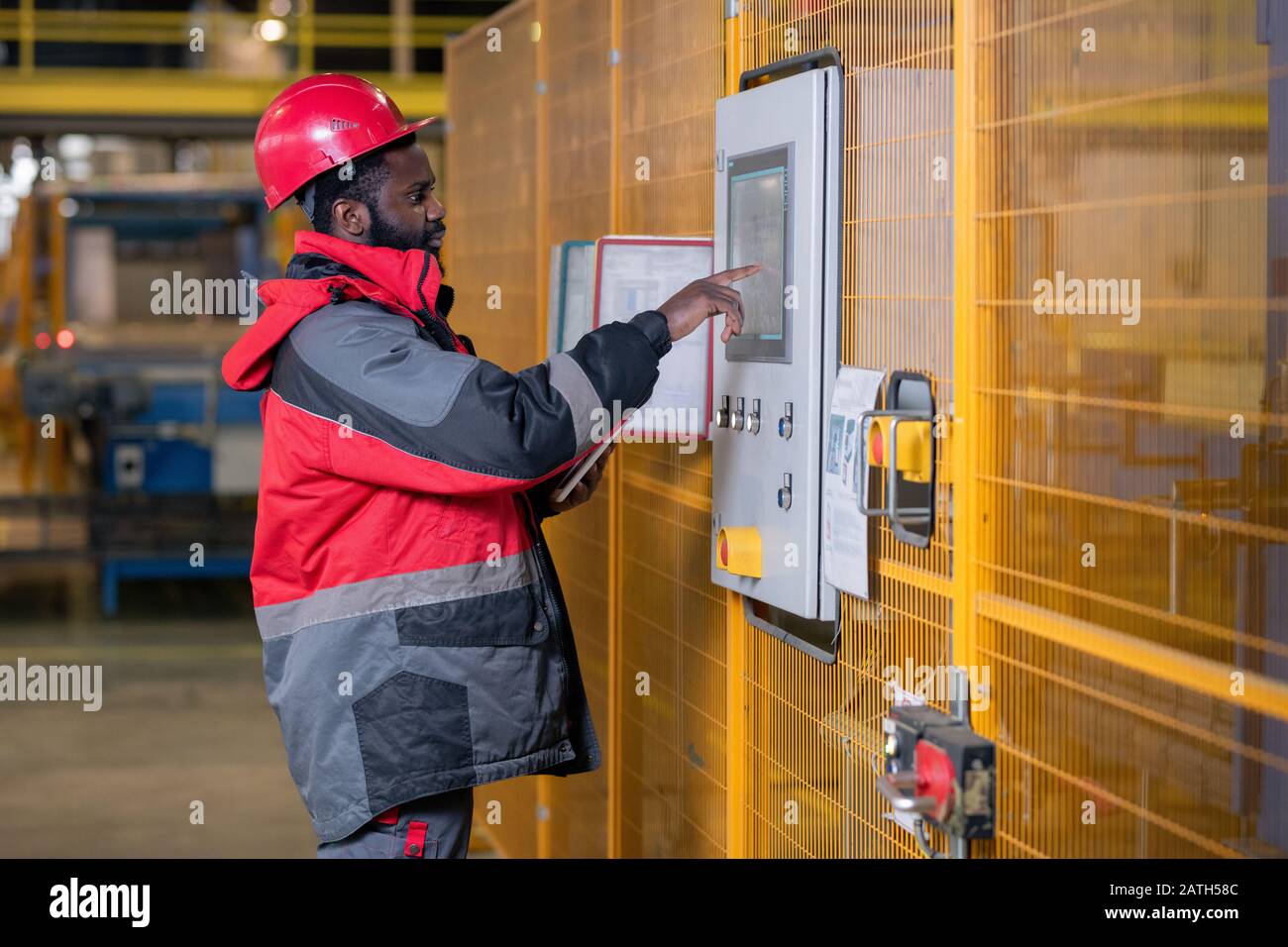 Serious young Black man in workwear and helmet choosing setups on control  panel in factory shop Stock Photo - Alamy