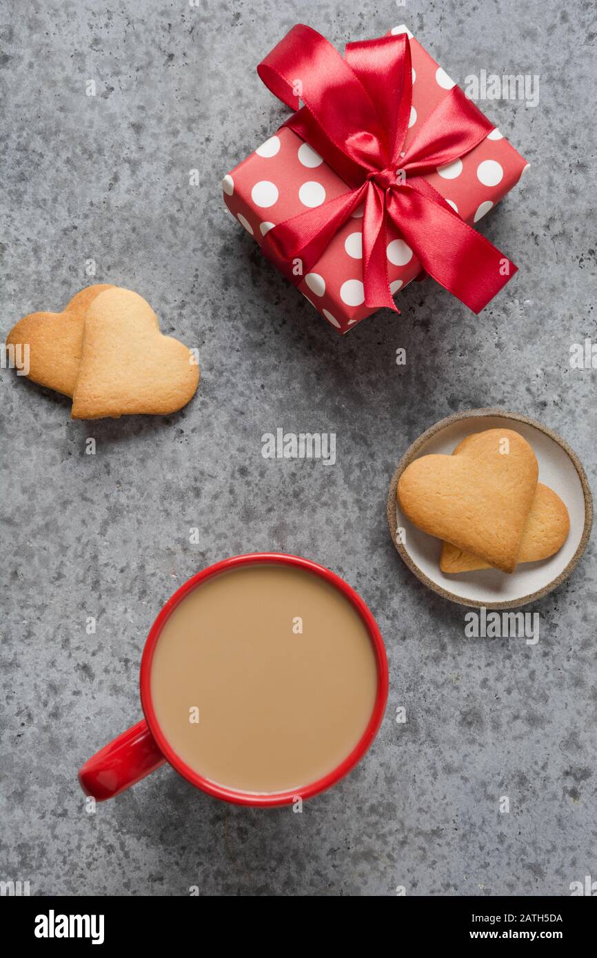 Valentines day greeting card with gift, homemade heart cookies and coffee cup on grey stone table. Top view. Vertical format. Stock Photo