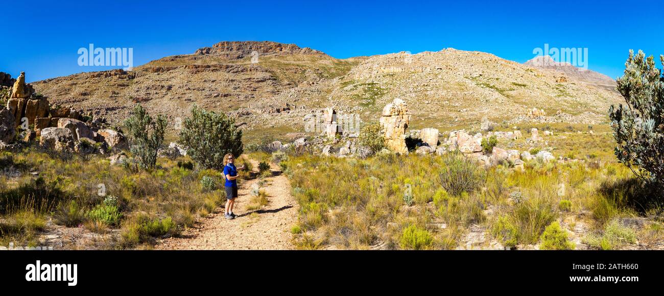 Panoramic view of the hiking trail to Maltese Cross - a popular hiking destination in the Cederberg Area (South Africa) with a young woman pointing to Stock Photo