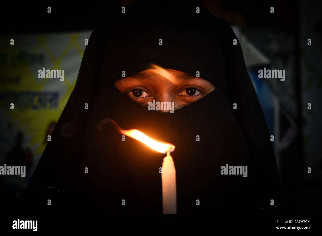 A Muslim woman is holding a candle on a candle march rally for protesting rape and woman's harassment in Kolkata, India. Stock Photo