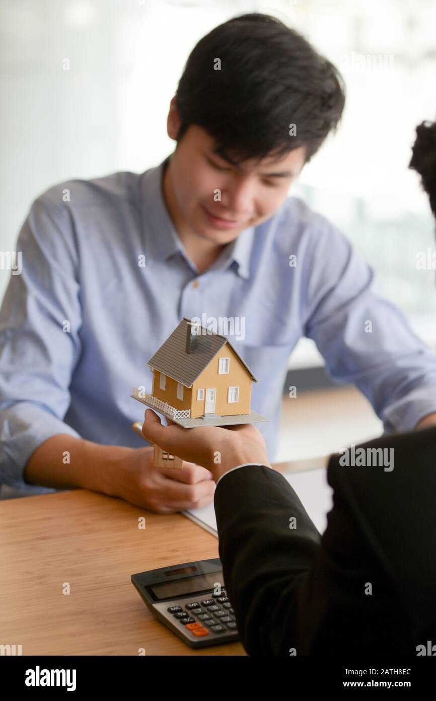 Close up view of Real estate agent holding house model while presenting ...