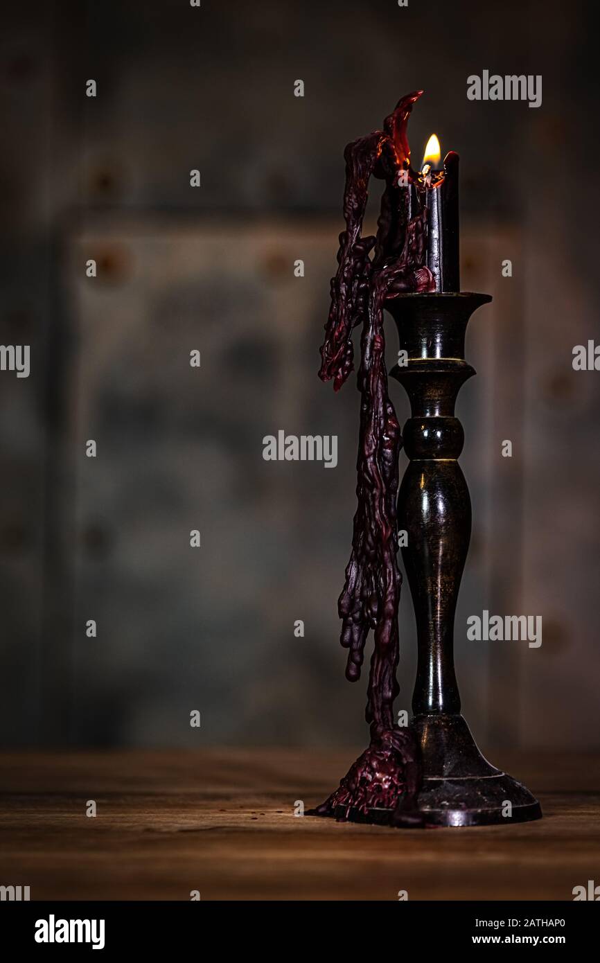 Candlestick with a black candle with candlelight and wax, wooden table